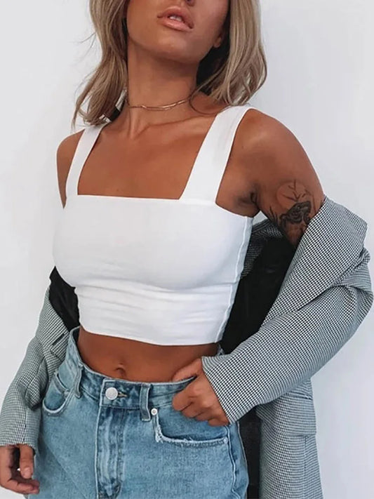 Person wearing a white crop top and blue jeans with a gray jacket over shoulders.